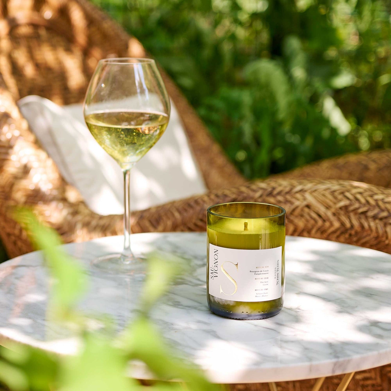 Maison Tchin Tchin, bougie artisanale upcyclée au parfum Sauvignon posée sur une table de jardin