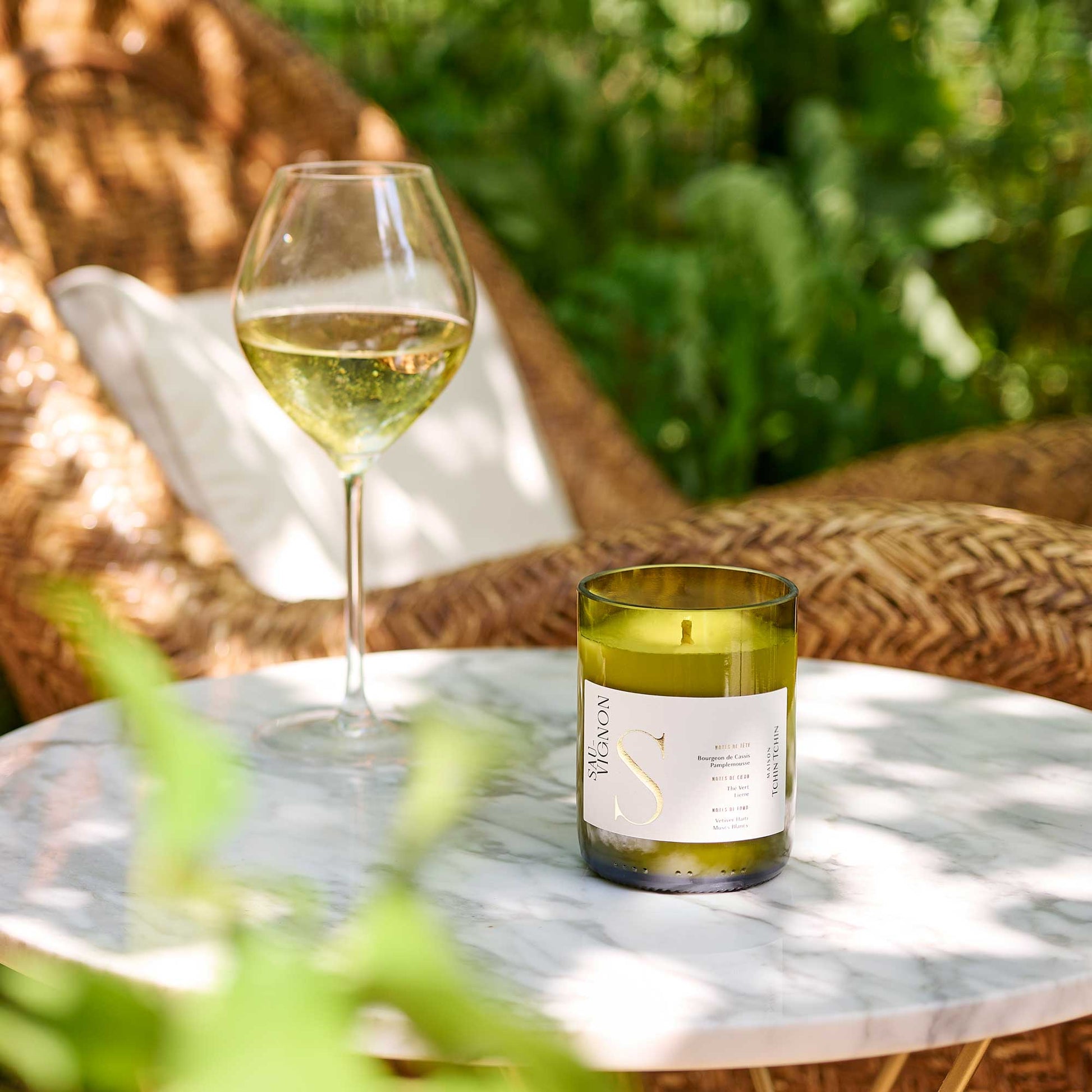 Bougie parfumée upcyclée parfum Sauvignon posée sur une table de jardin