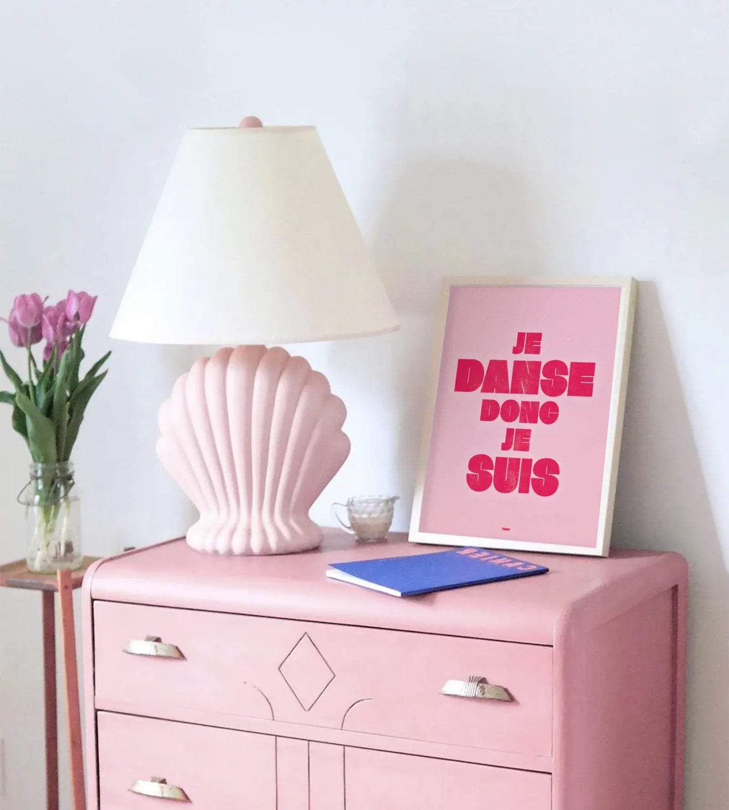 Affiche rose "Je danse donc je suis" par le Studio Topo posée sur un meuble dans une chambre