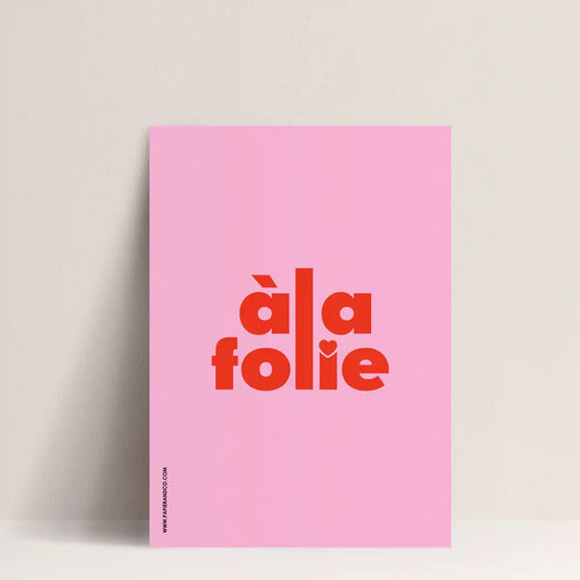 Affiche à message "à la folie" rose, de Papier and Co présentée sur un mur blanc