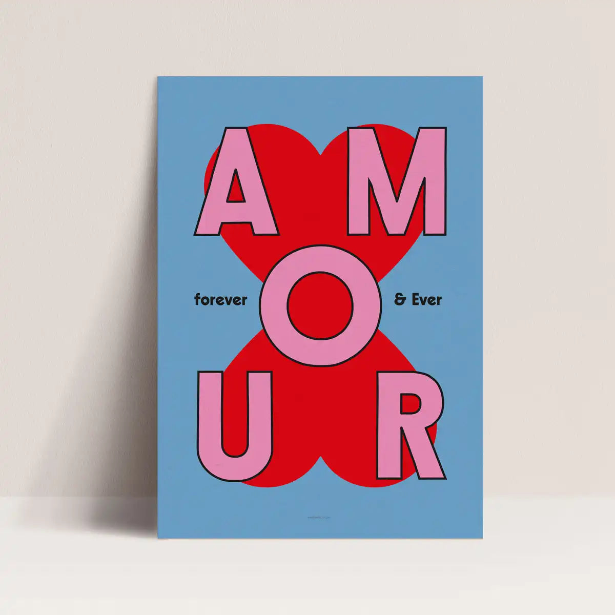 Affiche Amour forever and ever de Papier and Co en lettrage rose sur un fond bleu posée devant un mur blanc.