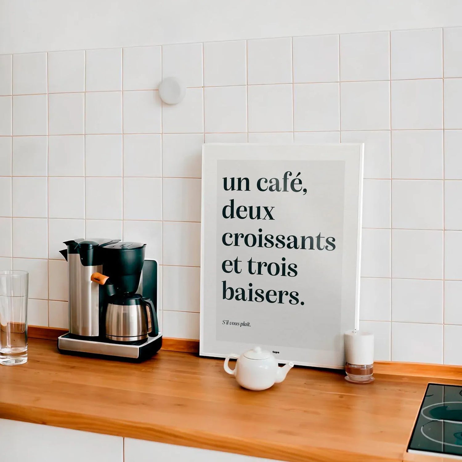 Affiche design en 30x40cm "Un café" de Studio Topo posée sur le plan de travail d'une cuisine