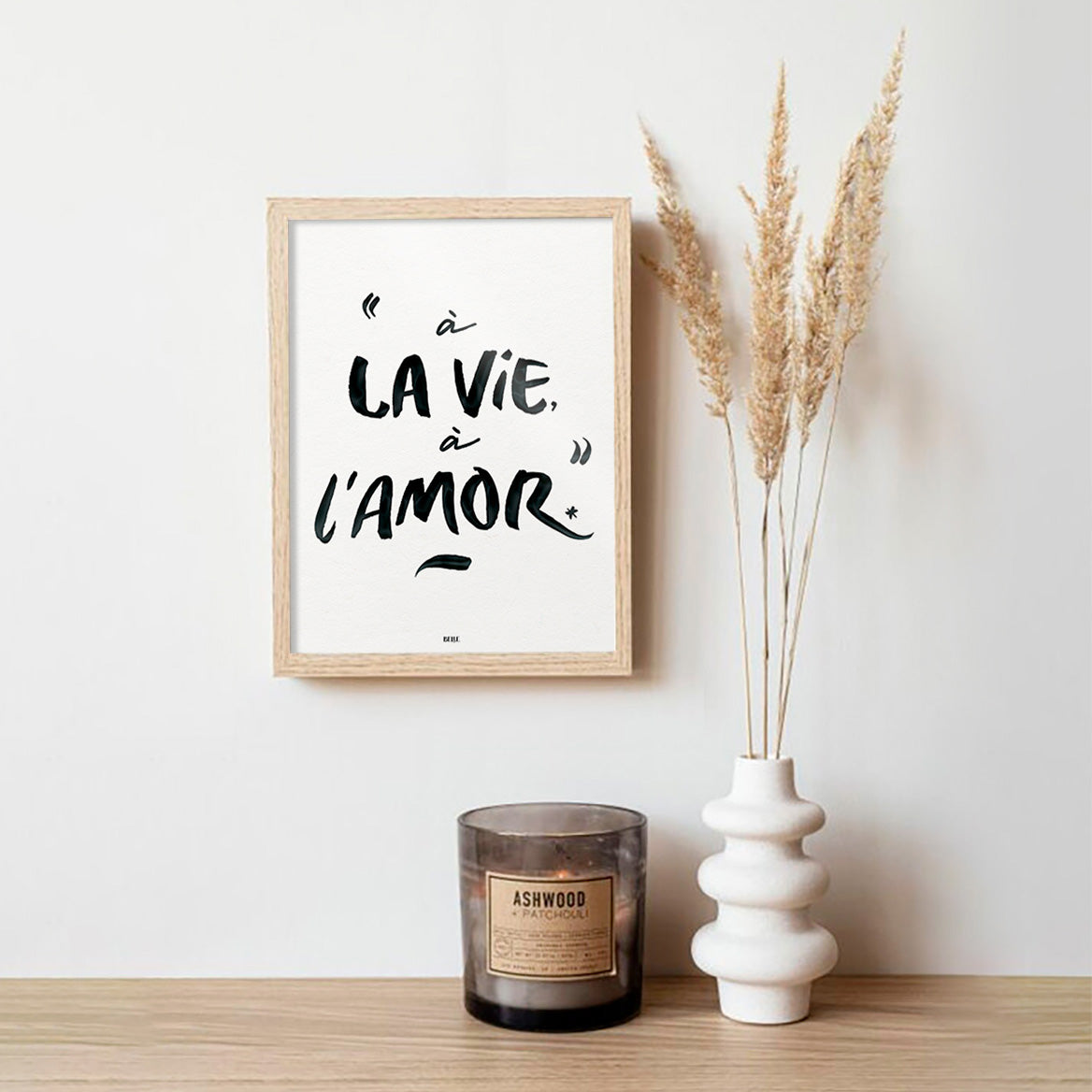 Affiche "À la vie, à l'amor" encadrée et accrochée au mur