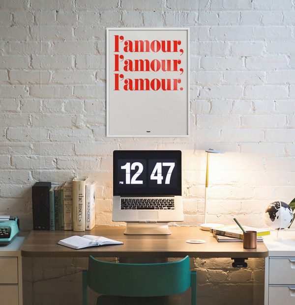 Affiche L'amour L'amour L'amour par Studio Topo accrochée sur un mur blanc au dessus d'un bureau