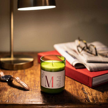 Bougie parfumée faite à la main, senteur merlot, posée sur un bureau en bois, sous une lampe à côté d'un livre