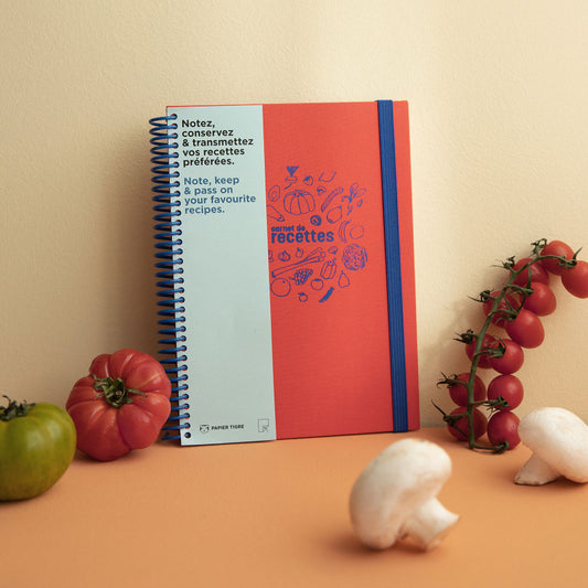 Carnet de recettes de cuisine Papier Tigre posé contre un mur avec des fruits et légumes posés de part et d'autre.