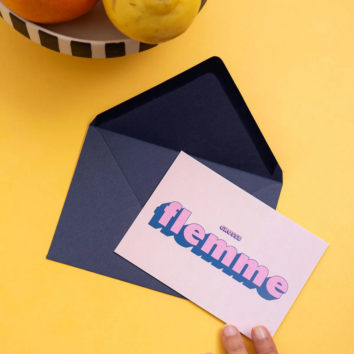 Carte Grosse Flemme avec son enveloppe de Papier and Co posée sur une table jaune