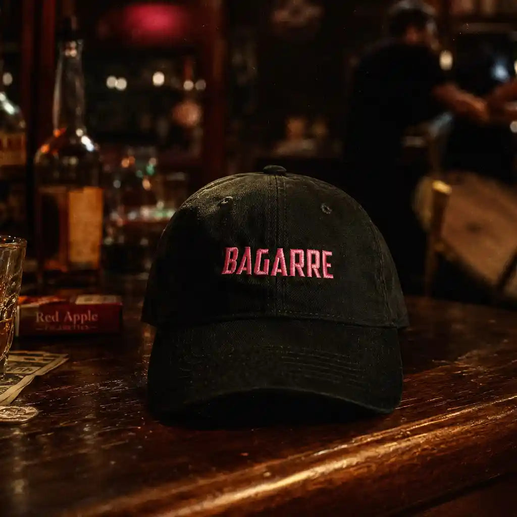 Casquette brodée à message bagarre noir et rose posée sur un bar