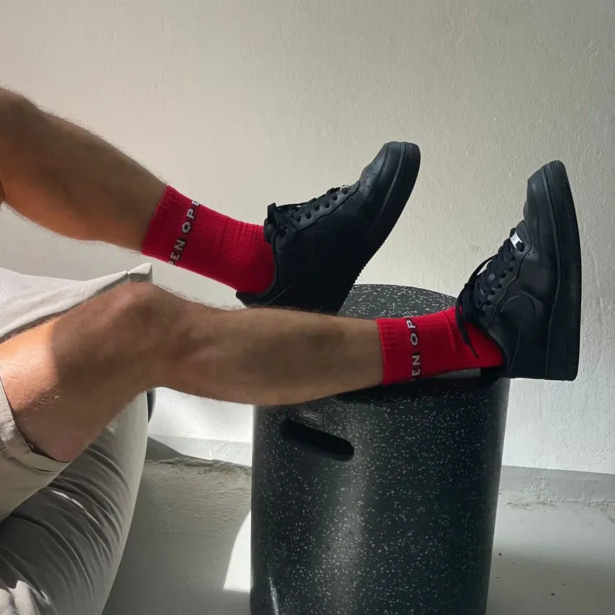 Chaussettes montantes rouge Open par Chaton Gonflable portées par un homme en short et baskets.