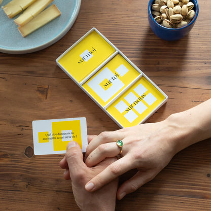Couple jouant au jeu pour couple 90 questions de la marque Complices pendant un apéritif.