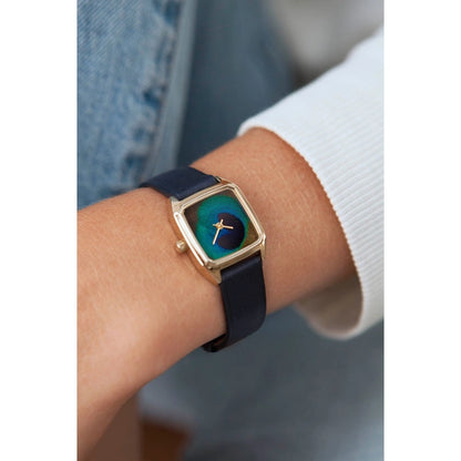 Femme portant la montre Laps Paon Or au poignet avec un bracelet de cuir bleu indigo