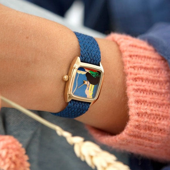 Montre pour femme Olympe de chez Laps avec un bracelet en perlon bleu au poignet d'une femme