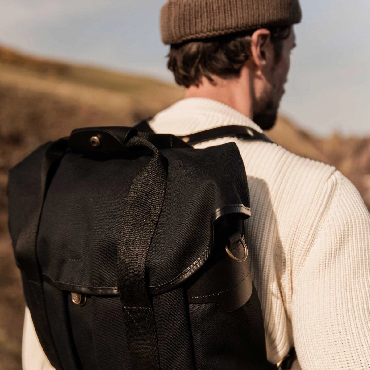 Détails de la fermeture du sac à dos en toile et cuir noir Chiloé de Bleu de Chauffe porté par un jeune homme